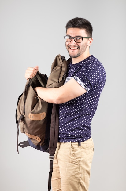 Young man standing and getting something out of his backpack