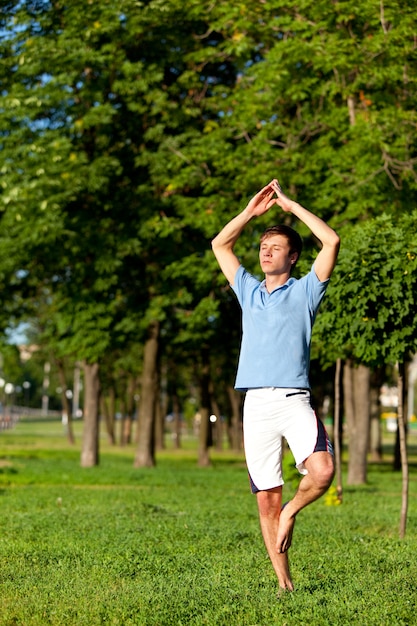 Young man standing on green grass and meditating