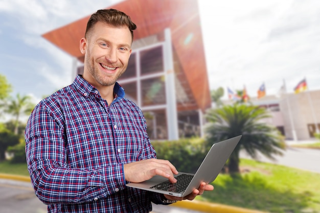 Young man standing, holding laptop computer