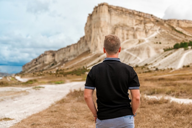 Young man standing and looking out over a huge white rock concept of travel and freedom Crimea