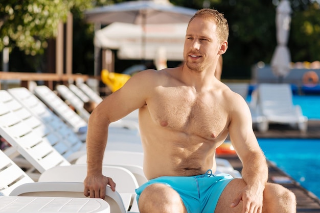 Young man standing near swimming pool having a great time