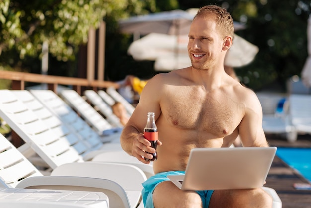 Young man standing near swimming pool having a great time