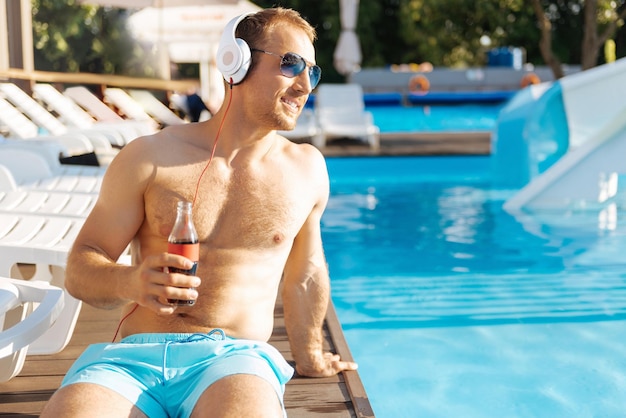 Young man standing near swimming pool having a great time