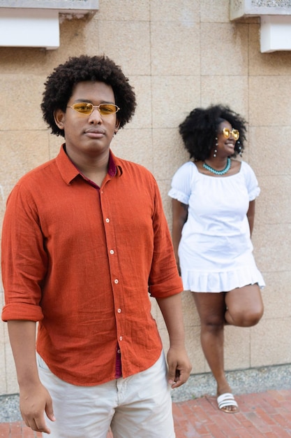 Young man standing in the street with her girlfriend behind her