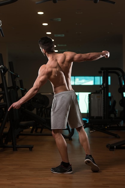 Young Man Standing Strong In The Gym And Flexing Muscles Muscular Athletic Bodybuilder Fitness Model Posing After Exercises