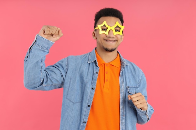 Young man in star glasses on pink background