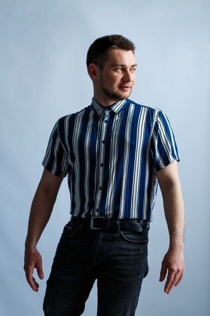 Young man in a striped classic shirt over white wall