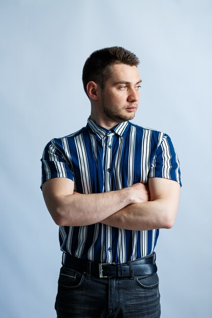 Young man in a striped classic shirt over white wall