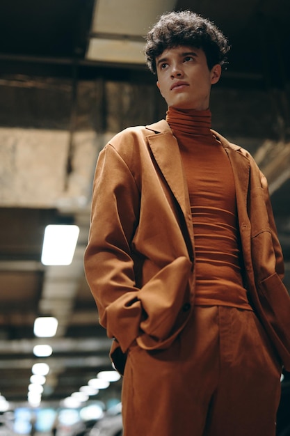 Photo young man in stylish brown outfit poses confidently in an urban setting the modern industrial