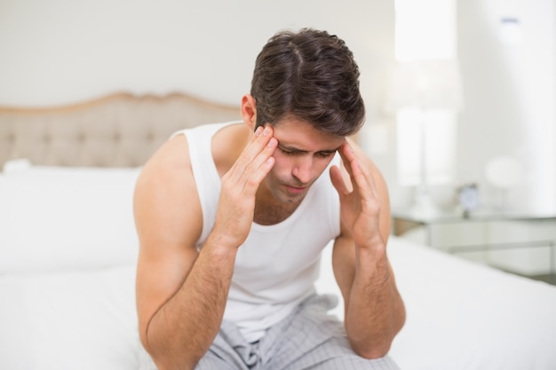 Young man suffering from headache in bed