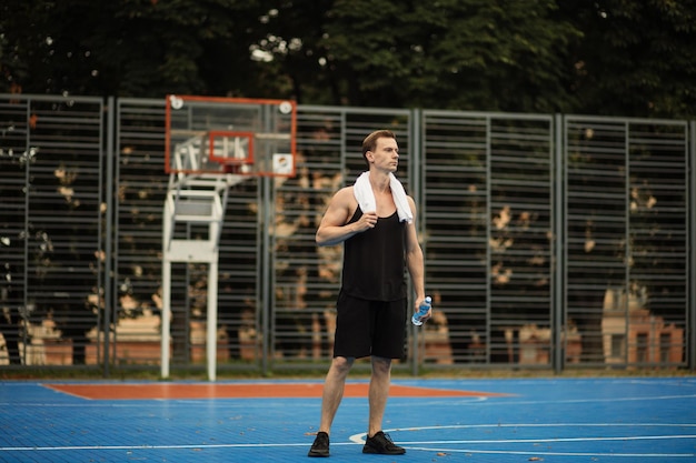 Young man in sweaty shirt resting after intense workout on outdoor gym