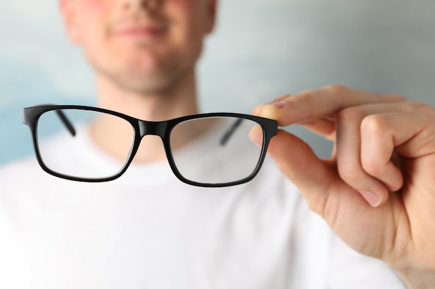 Young man in t - shirt hold glasses, close up