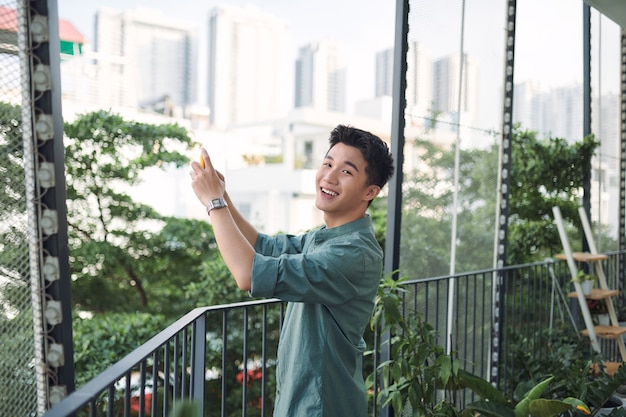 Young man takes photos with his phone of a beautiful view from the hotel's balcony