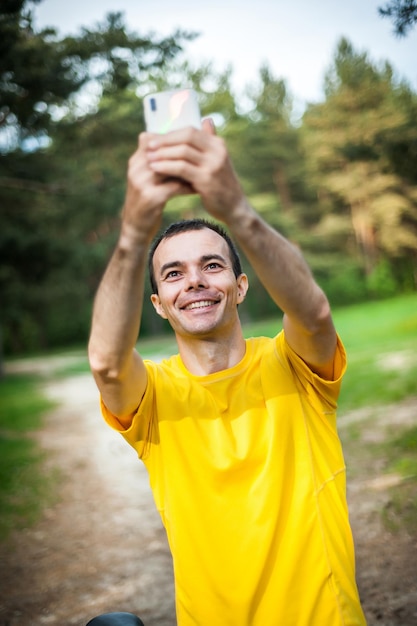 A young man taking a selfie with his Bicycle In a public Park among trees and vegetation