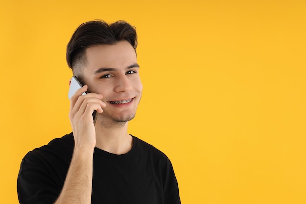 Young man talk on phone on yellow background