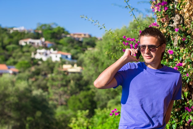 Young man talking on the phone at the balcony with beautiful view