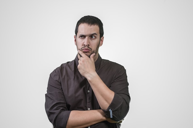 Young man thinking with his hand on his face and shirt