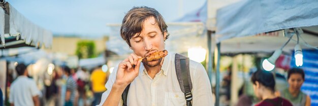 Young man tourist on Walking street Asian food market BANNER LONG FORMAT