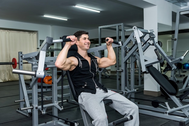 Young man training on sport equipment in gym