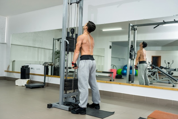 Young man training at sportive equipment in gym