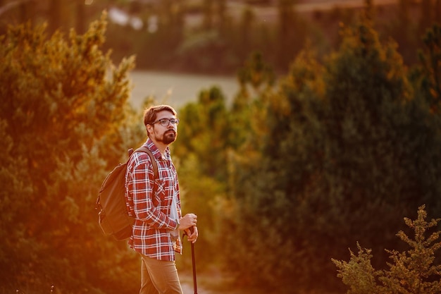 Young Man Traveler with backpack relaxing outdoor with rocky mountains on background