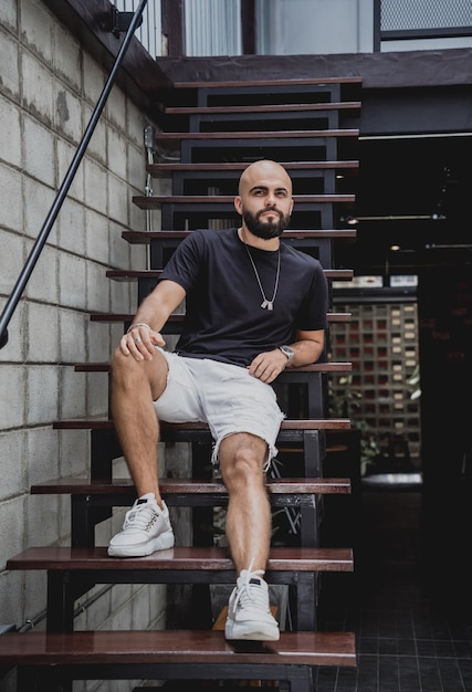 A young man in tshirt and shorts on the stairs at city streets