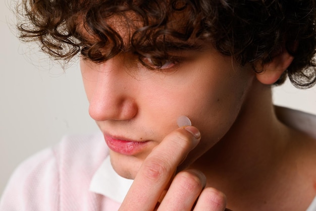 Photo young man uses acne stickers as bandage not to touch or squeeze pimple using acne pimple patch to clean the face from zits