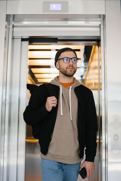 A young man uses an elevator IT specialist on the background of an elevator in an office building