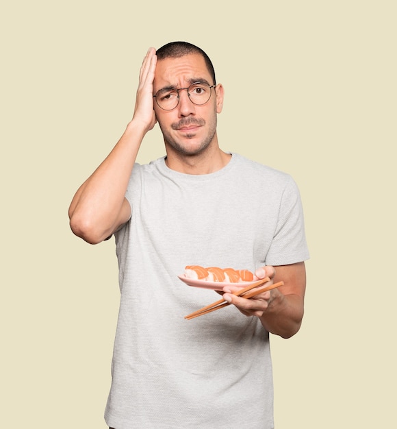 Young man using chopsticks to eat sushi