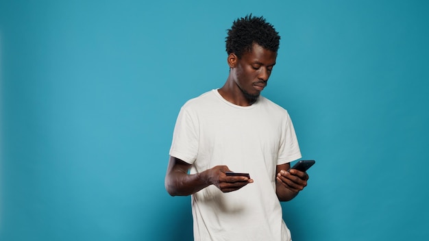 Young man using credit card for online shopping on smartphone. Portrait of modern person holding mobile phone and card to buy and shop on internet. Adult doing purchase on phone.