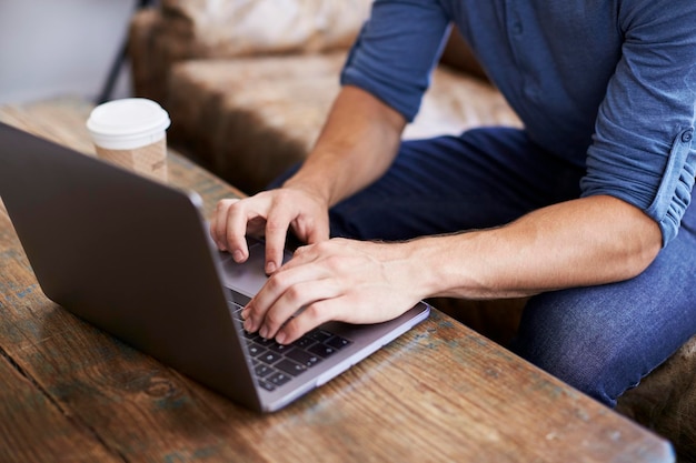 Young man using laptop in a coffee shop mid section