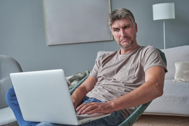 Young man using laptop and smiling at home