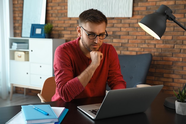 Young man using laptop at table indoors