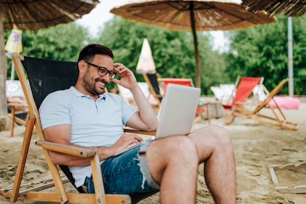 Young man using laptop while sitting on a beach chair.