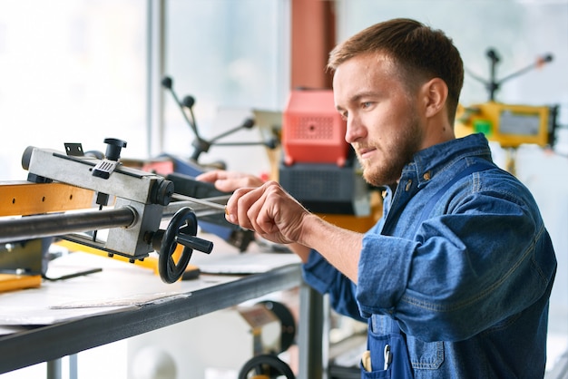 Young Man Using Machine Units at Factory