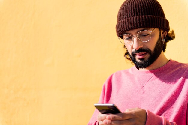 Young man using mobile phone in yellow background