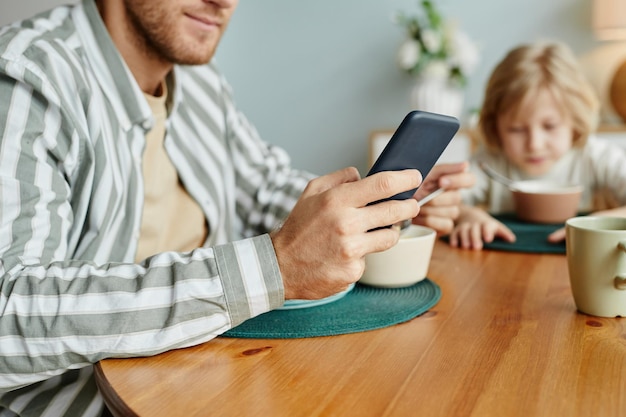 Young Man using Smartphone at Breakfast Closeup