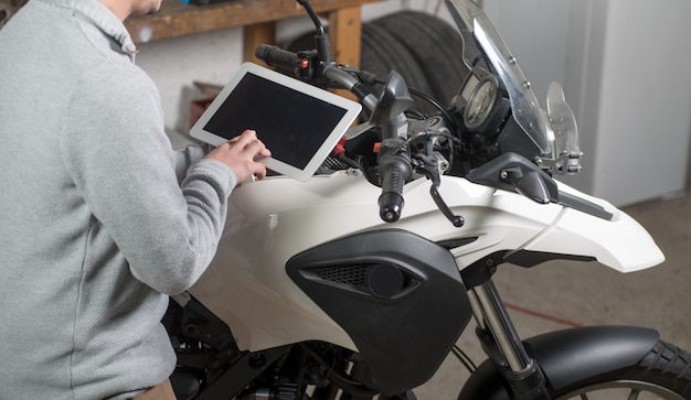 Young man using a tablet next to motorcycle