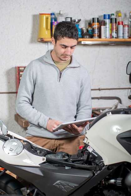 Young man using a tablet next to motorcycle