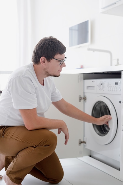 Young man using washing machine in laundry day at home