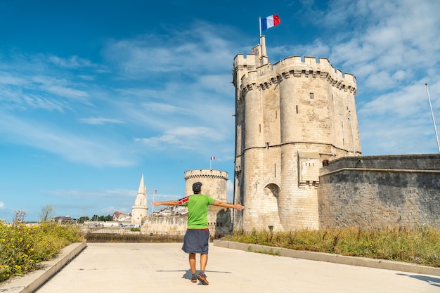 A young man on vacation next to Saint Nicolas Tower of La Rochelle in the summer. Coastal town in southwestern France