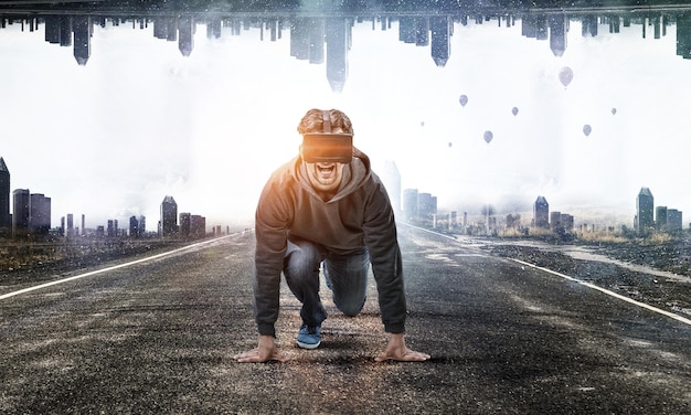 Young man in VR headset on start ready position on a road. Mixed media