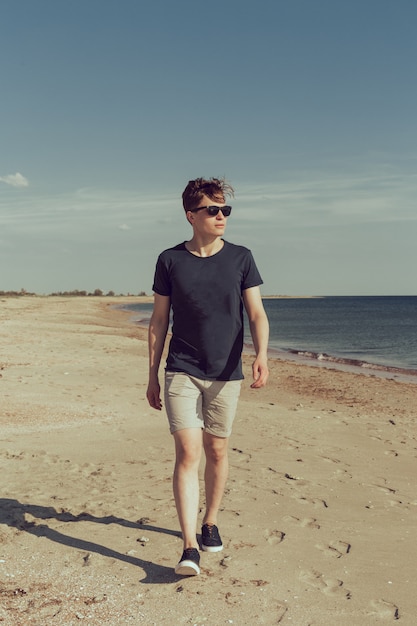 Young man walking along the seashore 