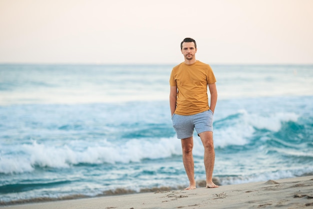 Young man walking on the beach at sunset