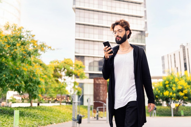 Young man walking by the city using a mobile phone