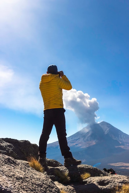 Young man walking on the mountain iztaccihuatl at dawn in the background the popocatepetl volcano