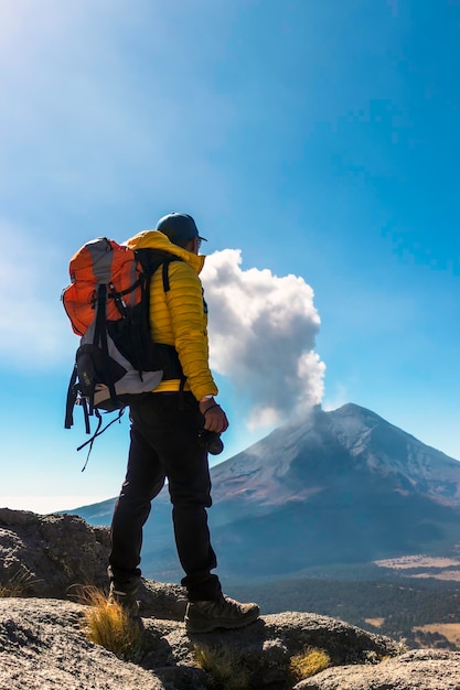 Young Man walking on the mountain iztaccihuatl at dawn in the background the Popocatepetl volcano