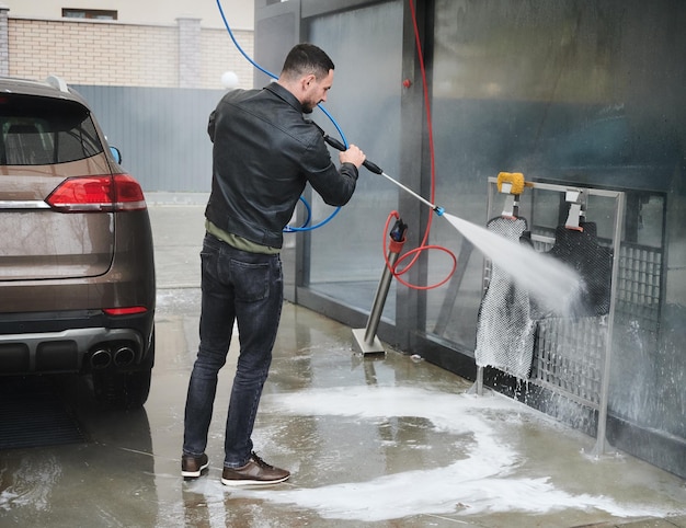 Young man washing car on carwash station outdoor