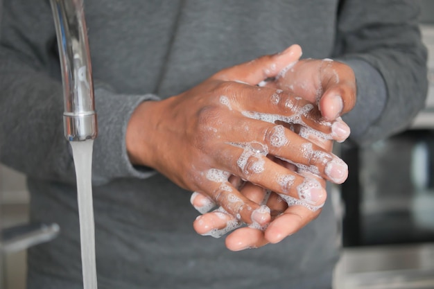 Young man washing hands with soap warm water