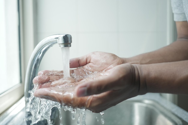 Young man washing hands with warm water